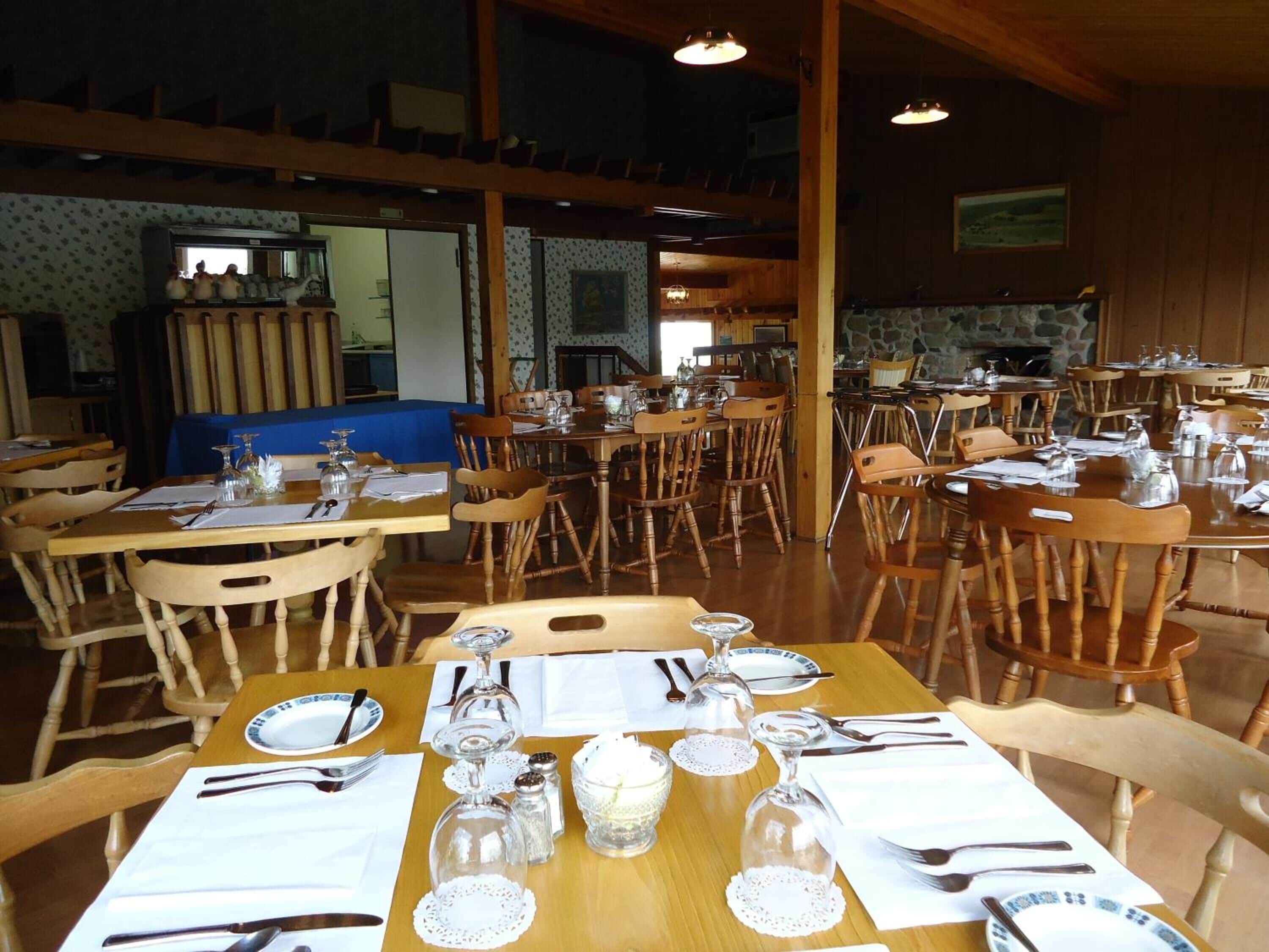A restaurant with wooden tables and chairs, set for dining with cutlery and glassware.