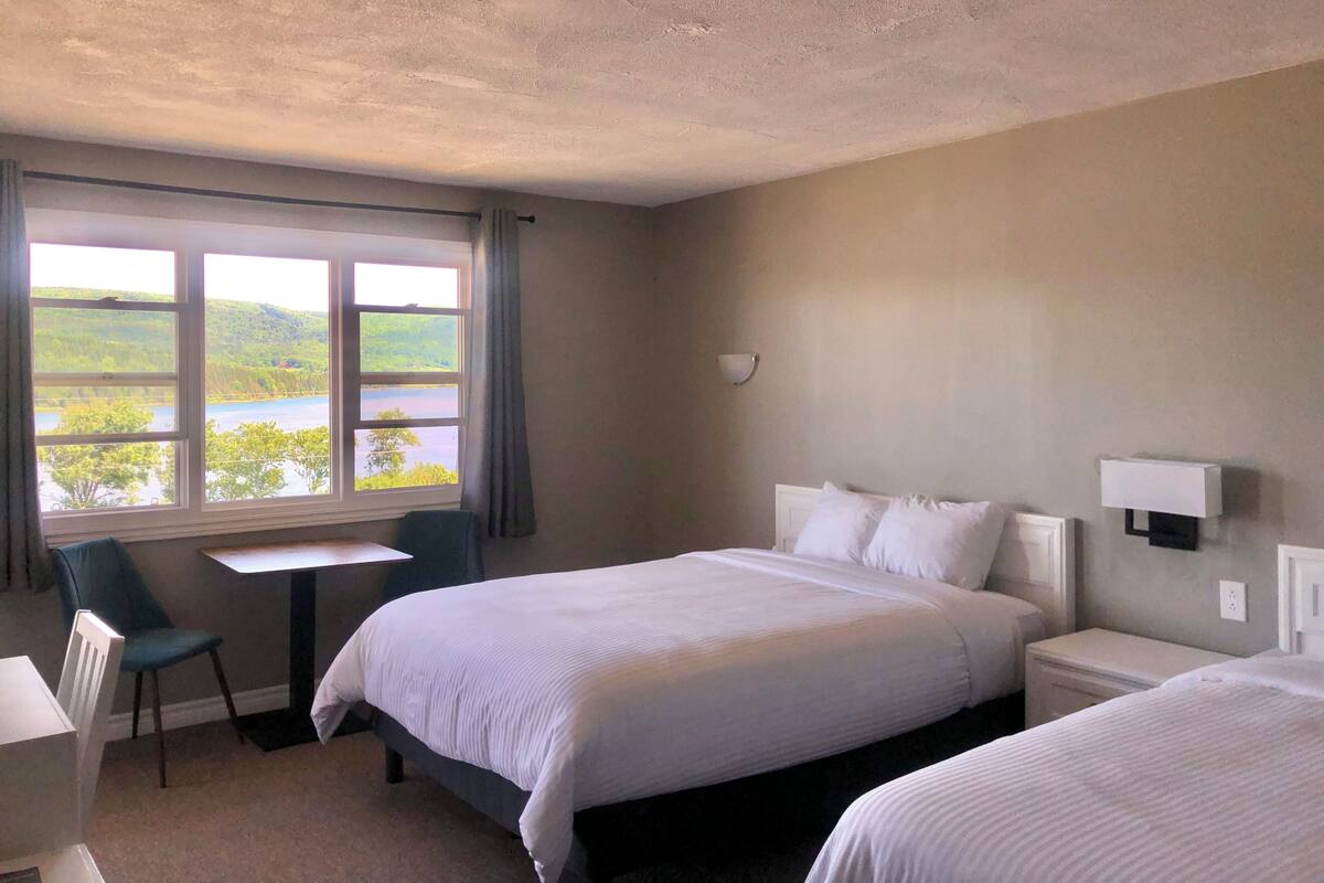 A hotel room with two beds, a desk, and a chair.
