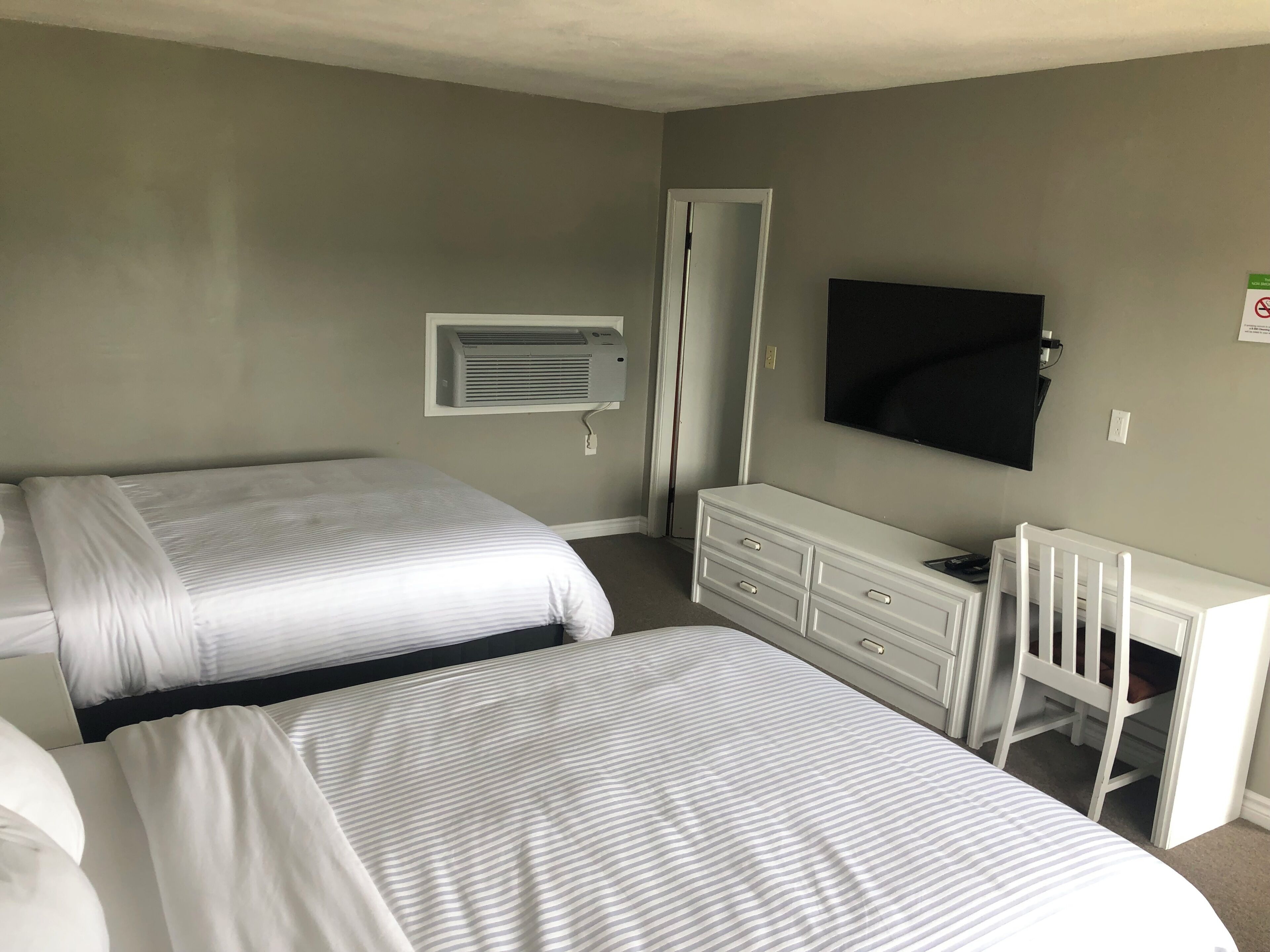 Een hotelkamer met twee bedden, een televisie, een bureau en een witte ladekast.