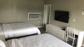 Een hotelkamer met twee bedden, een televisie, een bureau en een witte ladekast.