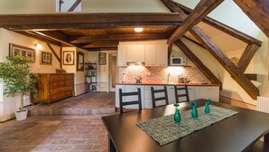 Una cocina acogedora con techo de madera, una mesa de comedor con sillas y una pequeña isla con un microondas.