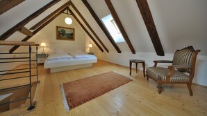 Un dormitorio con techo estilo loft, una cama, una silla y una mesita.