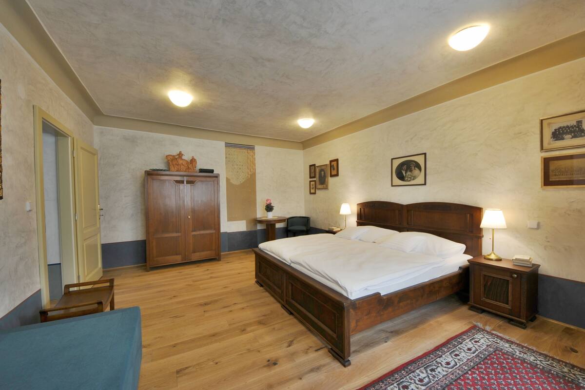 Une chambre à coucher avec un lit en bois, des tables de chevet avec des lampes, une armoire et un petit bureau.