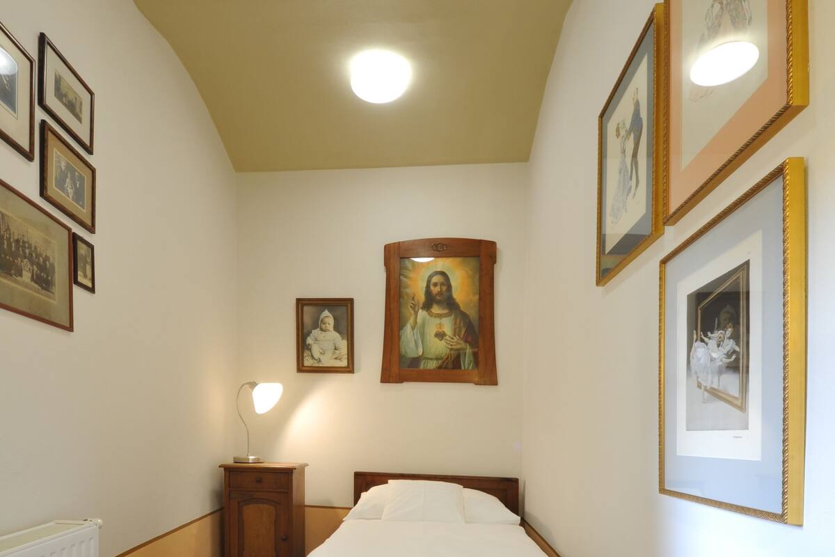 Une chambre à coucher avec un lit en bois, une table de chevet, une lampe fixée au mur et des tableaux encadrés accrochés aux murs.