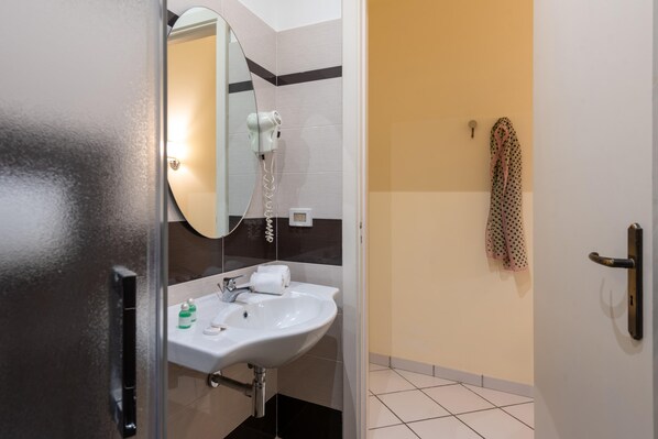 A bathroom with a white sink, a mirror, a hairdryer, and a towel rack.