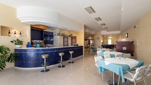 Een moderne bar met een blauw mozaïekteelwerk aanrecht, barstoelen en een diversiteit aan flessen en glazen.