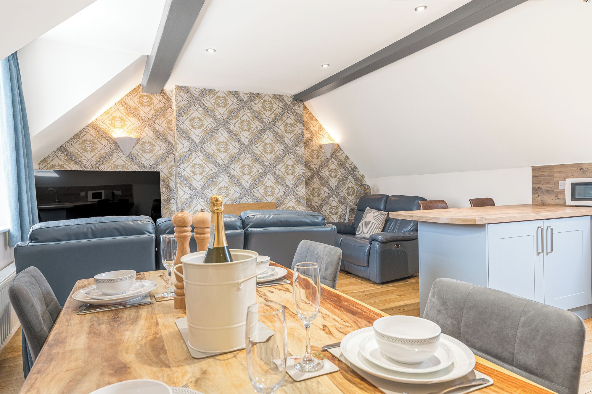 Un appartement moderne de style « loft » comprenant un coin repas, un salon avec canapé et une kitchenette.