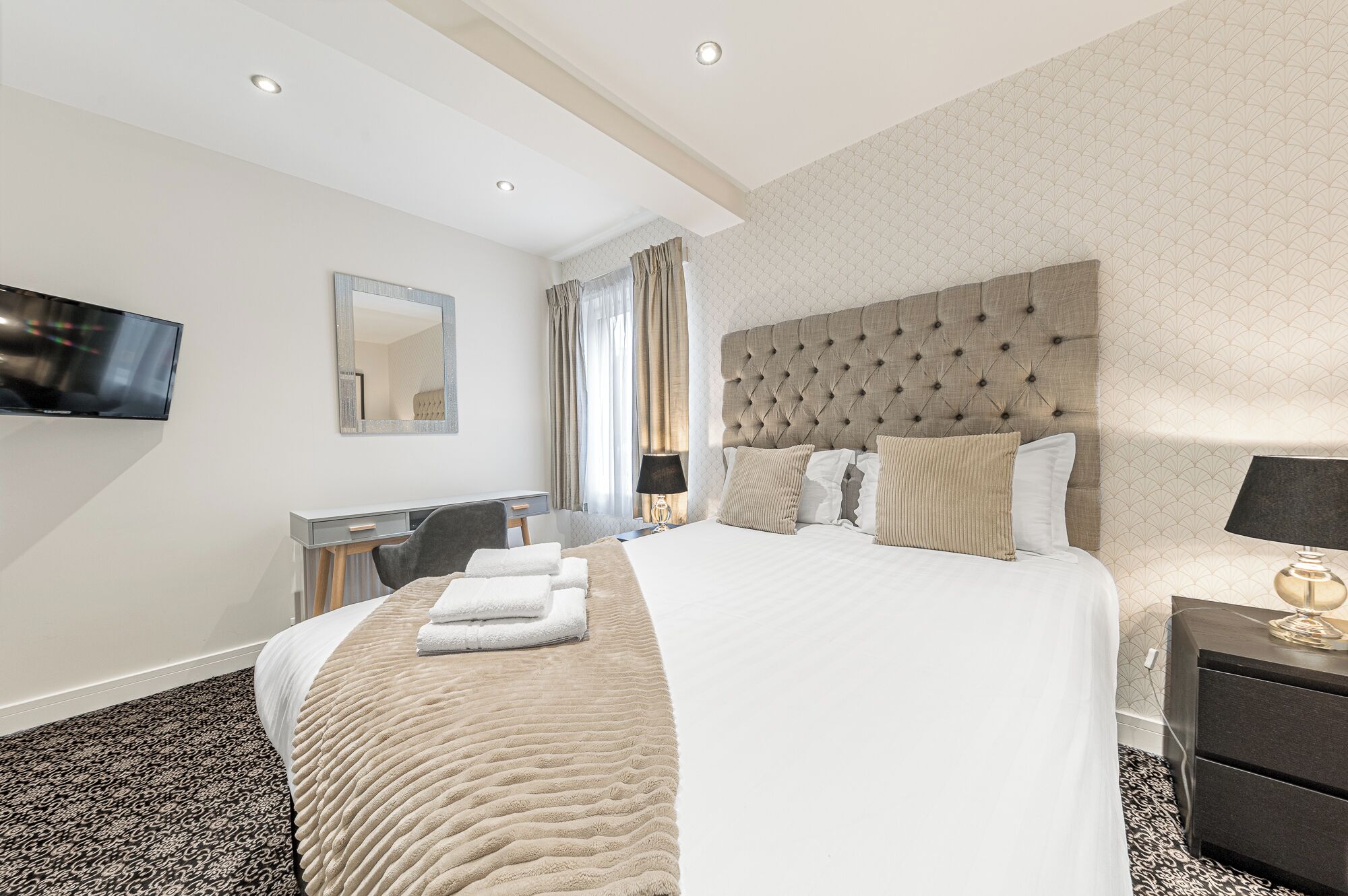 Une chambre d’hôtel avec un grand lit, un bureau, une chaise, une télévision et une table de chevet.
