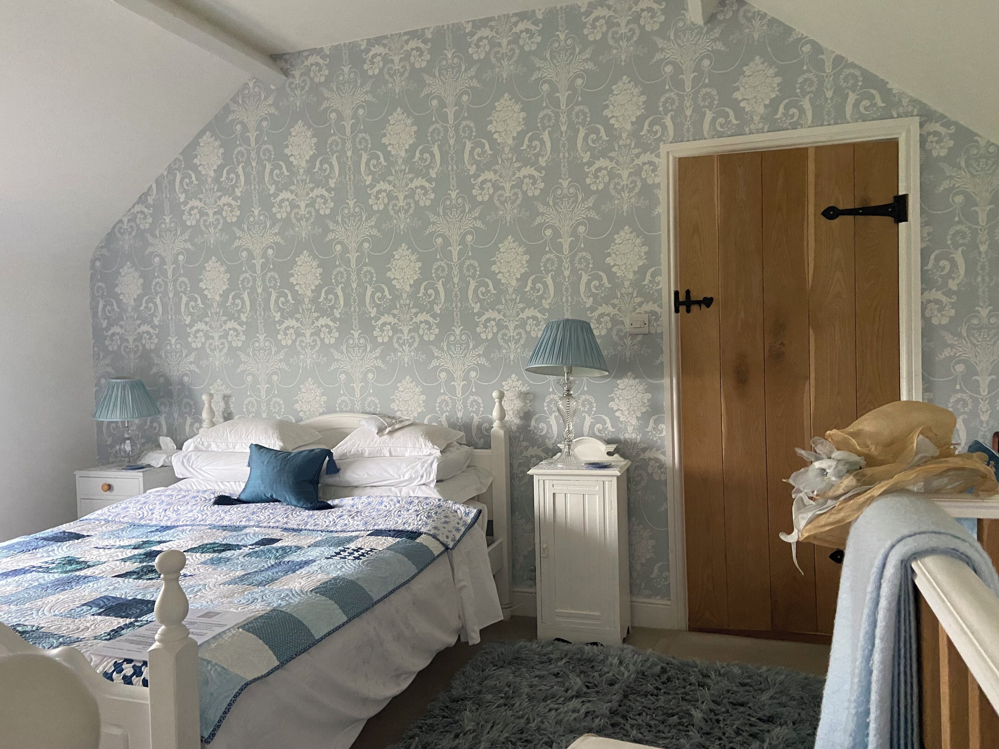 Una camera da letto con un letto, due comodini, un tavolo da notte, una lampada, una porta e una parete decorata.