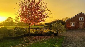 A house with a brick exterior, a visible front door, and a small front yard with a tree and grass. - Abbey Green Farm B&b, Camping & Touring Park (Whitchurch)