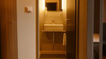 Un pasillo estrecho que lleva a un baño con lavabo y espejo.