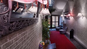 A hallway with a red carpet, a mirror with ornate designs, and a potted plant. - Pension Falconi (Kolin)