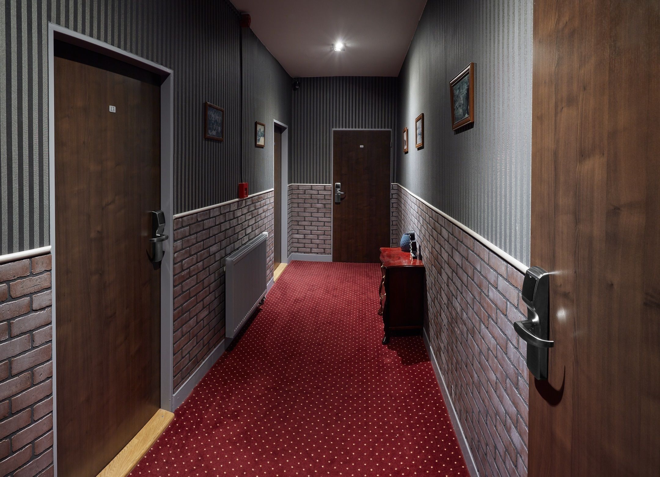 A hallway with striped walls, a red carpet, and a wooden door.