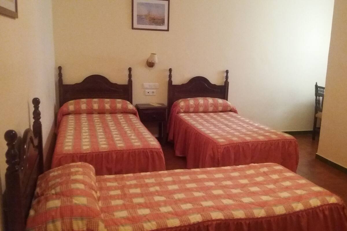 Una habitación con dos camas individuales, cada una con una colcha de cuadros y cabeceros de madera.
