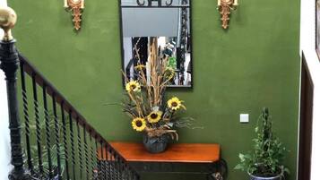 A staircase with a black railing, a wooden bench, a mirror, wall sconces, and a potted plant.