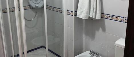 Un baño con ducha de vidrio, un bidé y un inodoro.