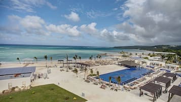 A resort with a large pool, beach area, and ocean view.