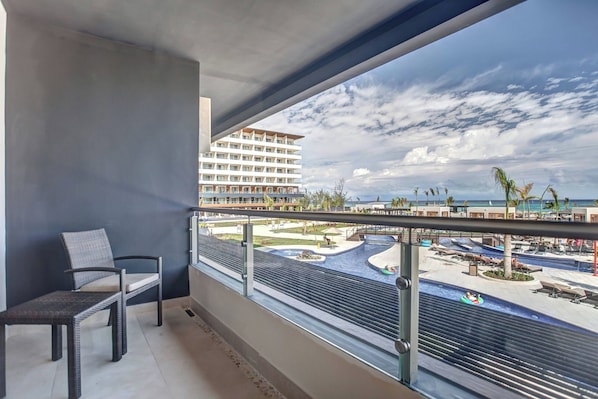 A balcony with a view of a resort pool area, including a water slide and lounge chairs. - Royalton Blue Waters Montego Bay, An Autograph Collection Resort (Falmouth)