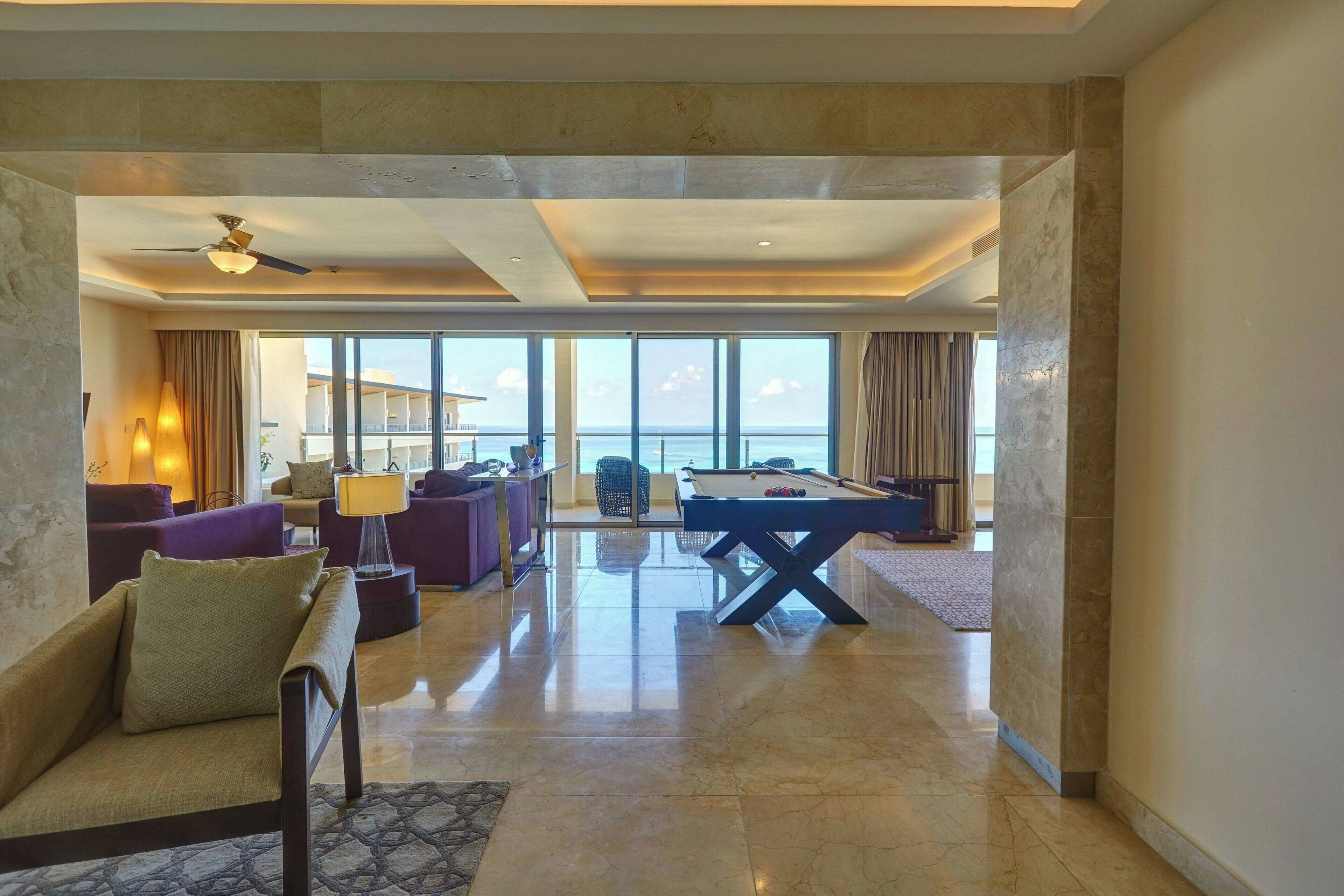 Un salón amplio con mesa de billar, asientos cómodos y vista al mar.
