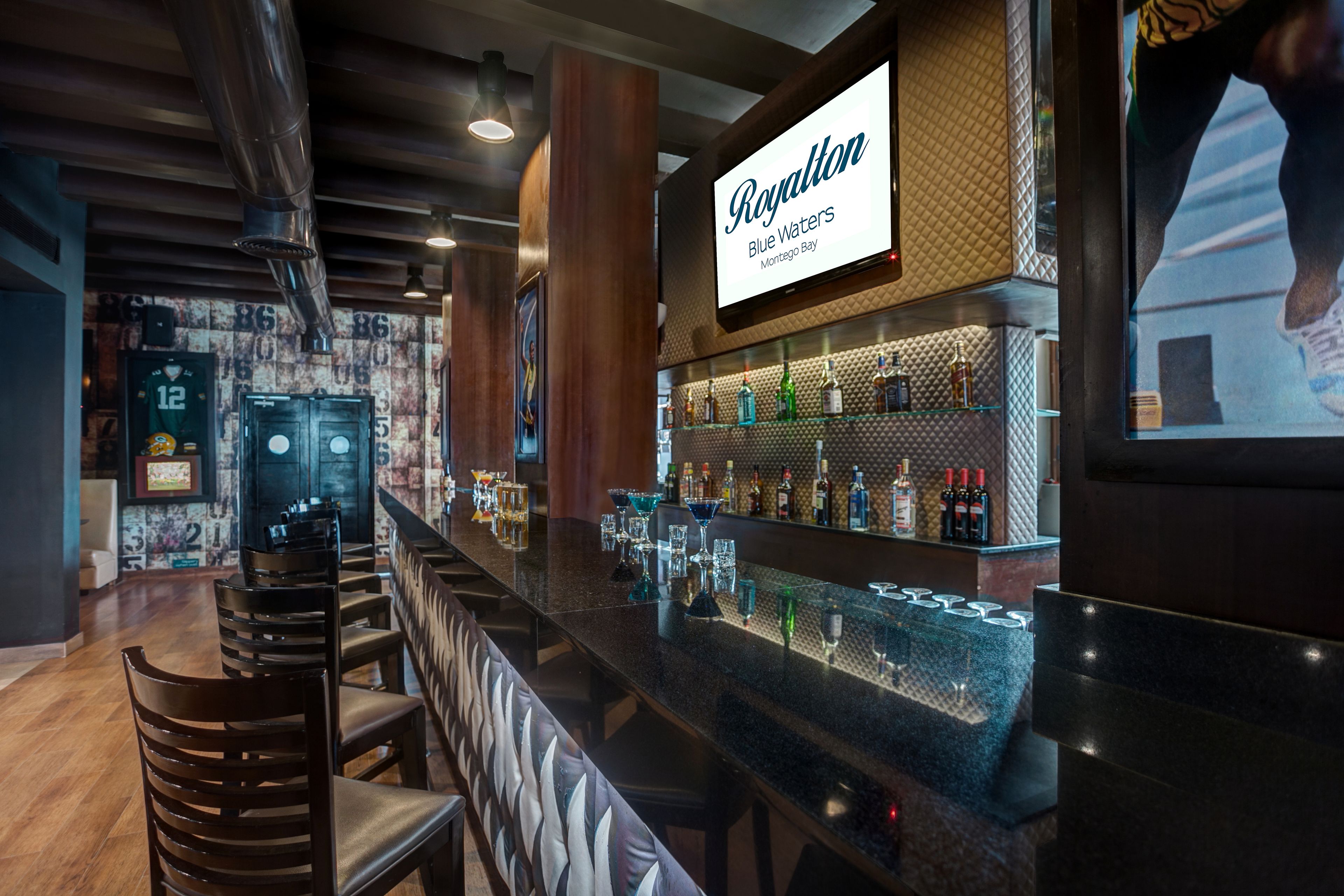 A bar area with a sign for 'Royalton Blue Waters' and a selection of liquor bottles.