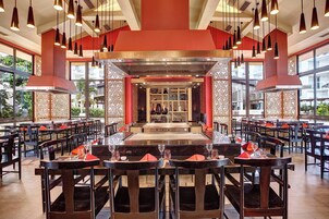 Un restaurante con varias mesas y sillas, una barra central y amplios ventanales con vistas al exterior.