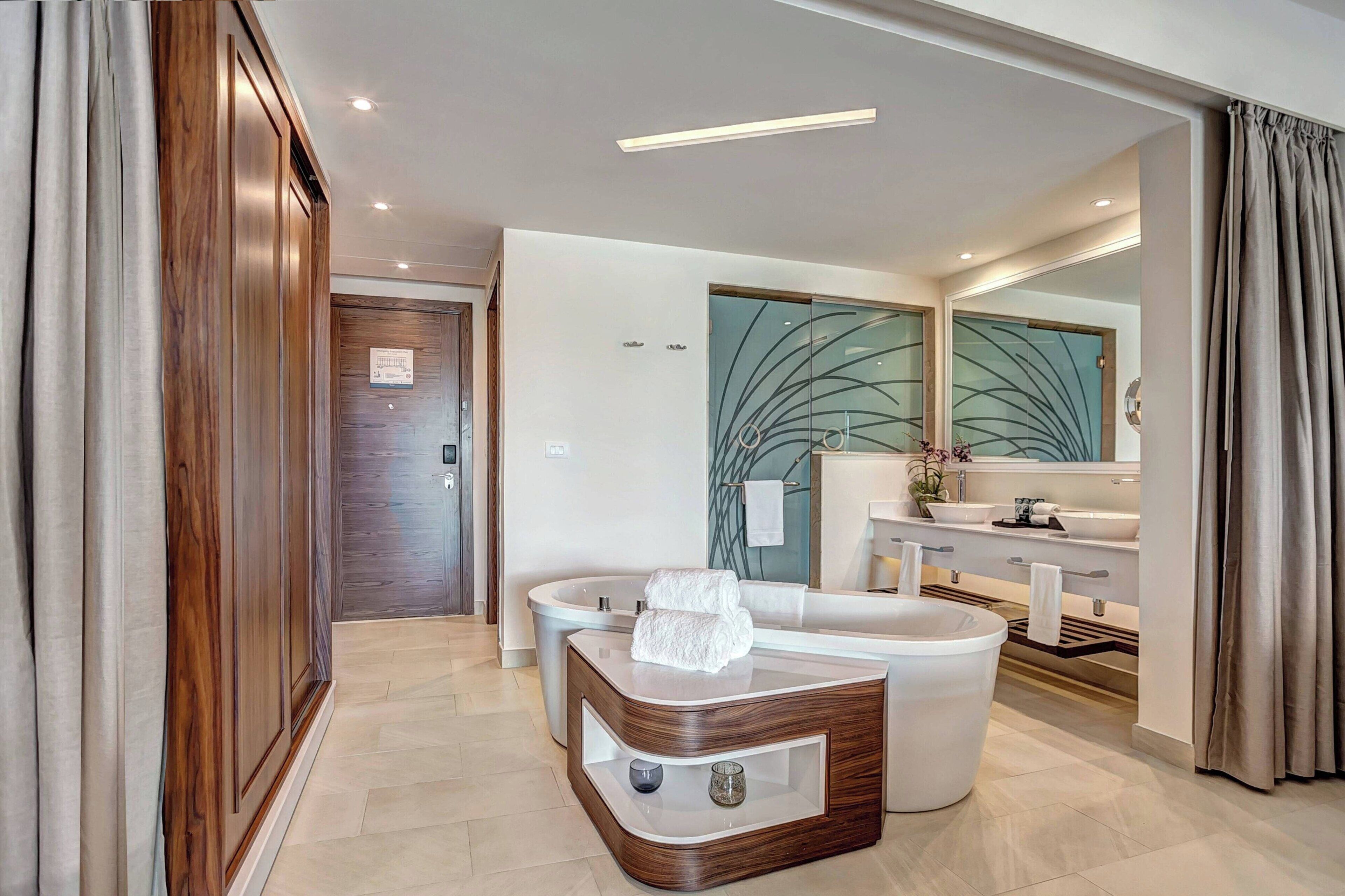 A modern bathroom with a freestanding bathtub, a vanity with a mirror, and a decorative wall panel.