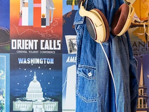 Una chaqueta vaquera con auriculares colgando, un cartel con la inscripción 'ORIENT CALLS' y 'WASHINGTON', y una vista parcial de un edificio con aguja.