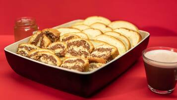 A tray of sliced pastries and a glass of dark beverage on a red surface.