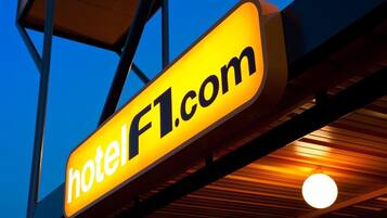 Un letrero de hotel con el texto 'hotelF1.com' sobre un fondo de cielo azul.