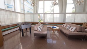 A spacious living area with a foosball table, two sofas, and a coffee table. - Hotel Ambra (Lignano Sabbiadoro)