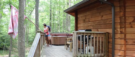 Una cabaña de madera con terraza, jacuzzi y zona de barbacoa.