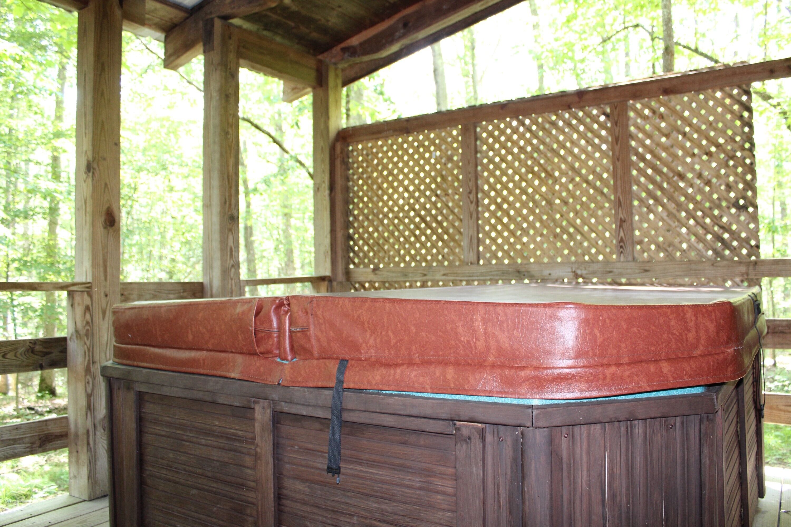 A wooden cabin with a covered hot tub.
