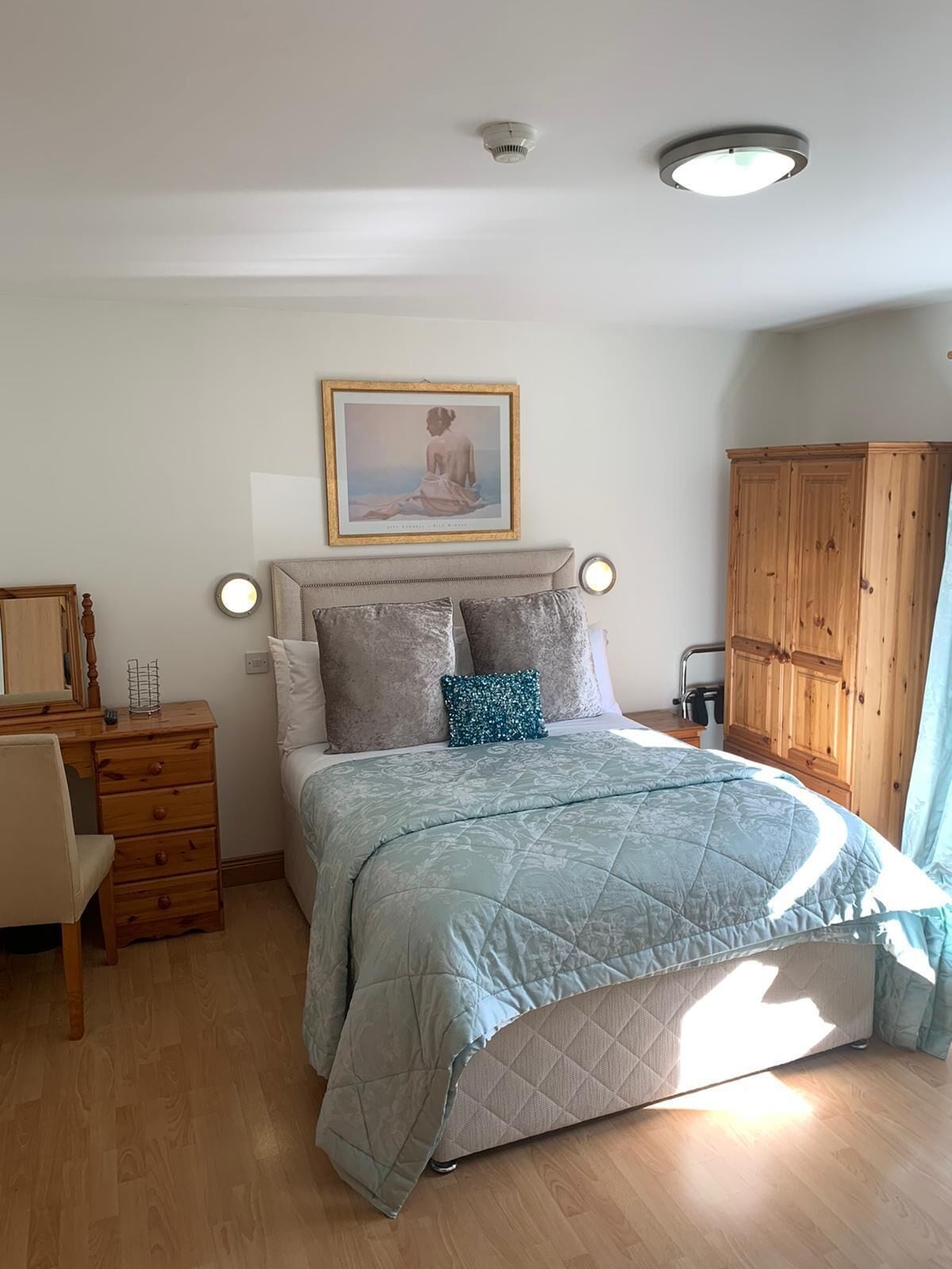 A bedroom with a bed, dresser, and wardrobe.