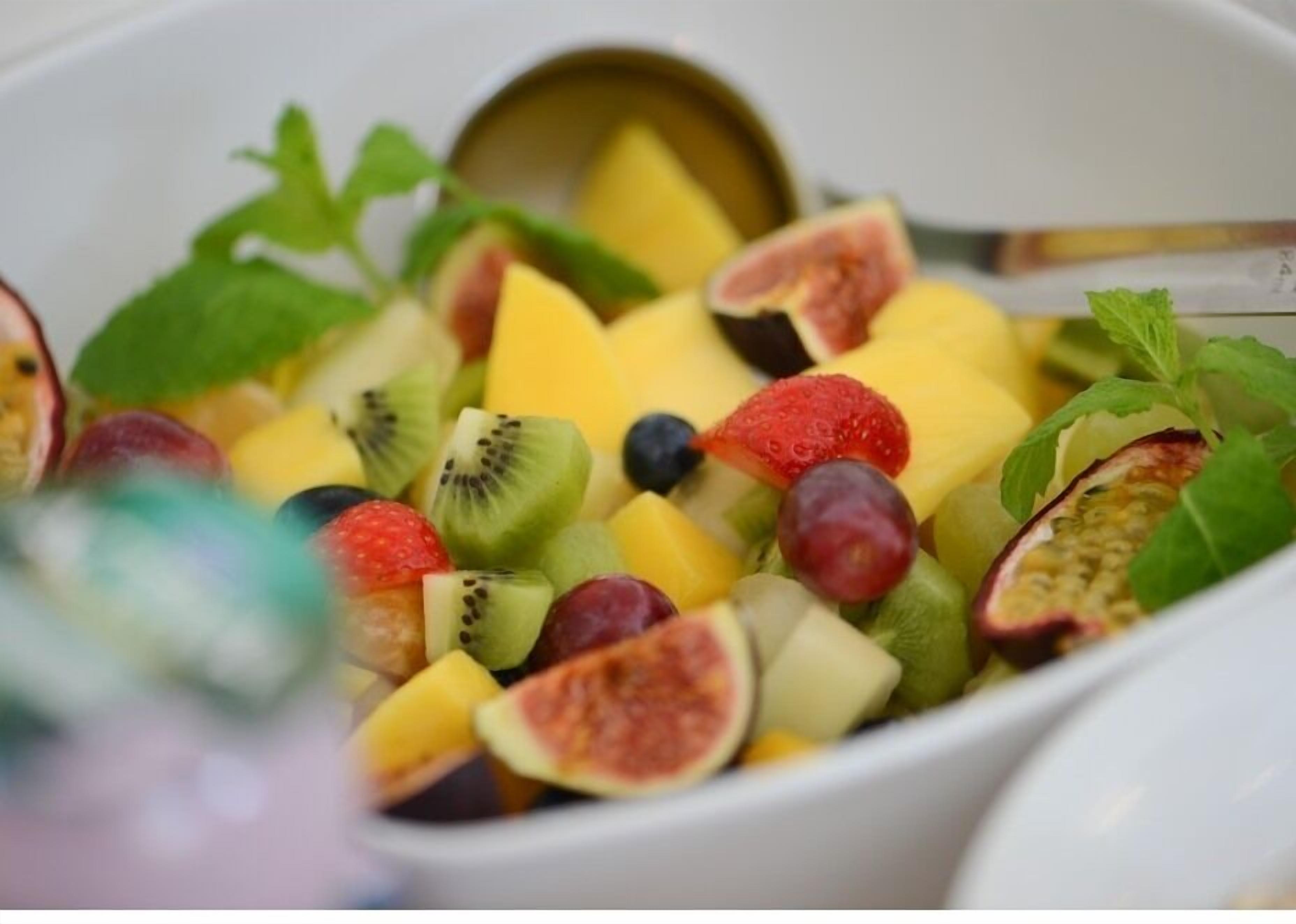 A bowl of mixed fruit salad with a spoon.