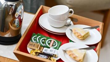 A tray with a coffee maker, cups, saucers, and food items.