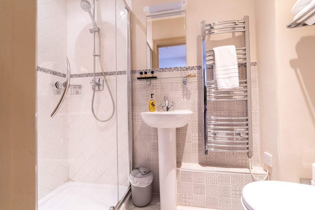 Ein modernes Badezimmer mit einer Duschkabine, einem Standwaschbecken und einem Handtuchhalter.