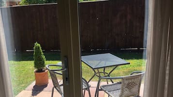 Eine Terrasse mit Tisch und Stühlen, einem Topfpflanzen und einem Holzzaun.