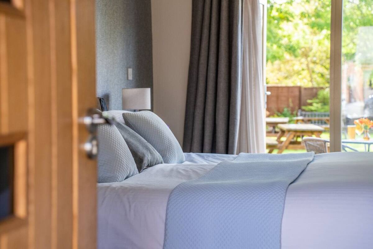 A bedroom with a bed, a nightstand, and a window with curtains.