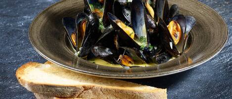 A dish of mussels served on a plate with two slices of bread.