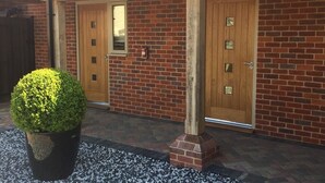 Un bâtiment en briques avec deux portes en bois et un pot de fleurs au premier plan.
