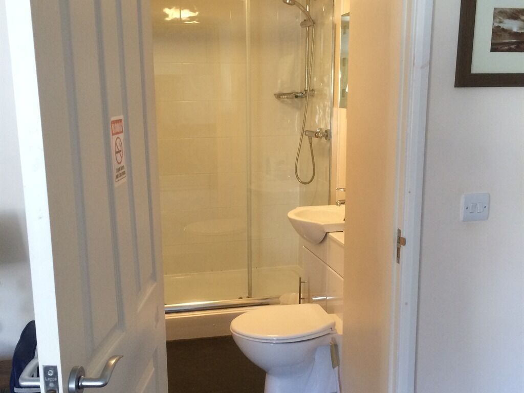 A bathroom with a glass-enclosed shower, a white toilet, and a sink.