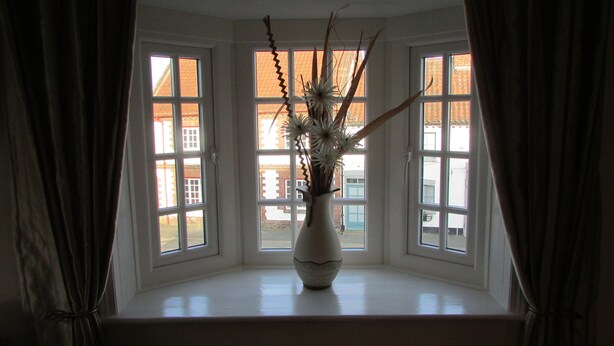A room with a bay window, a white radiator, and a vase with branches and flowers. - The Southgate Bed And Breakfast (Filey)