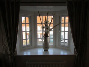 A room with a bay window, a white radiator, and a vase with branches and flowers. - The Southgate Bed And Breakfast (Filey)