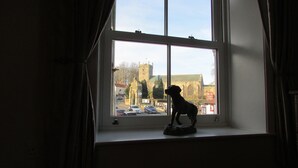 A window with a statue of a dog on the sill, overlooking a town with historic buildings and a church. - The Southgate Bed And Breakfast (Filey)
