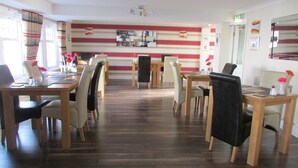 A dining area with striped walls, wooden tables, and chairs. - The Southgate Bed And Breakfast (Filey)