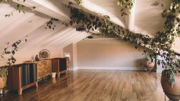 An attic room with wooden flooring, a wooden cabinet, and a ceiling with hanging vines.