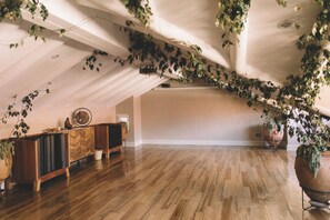 An attic room with wooden flooring, a wooden cabinet, and a ceiling with hanging vines.