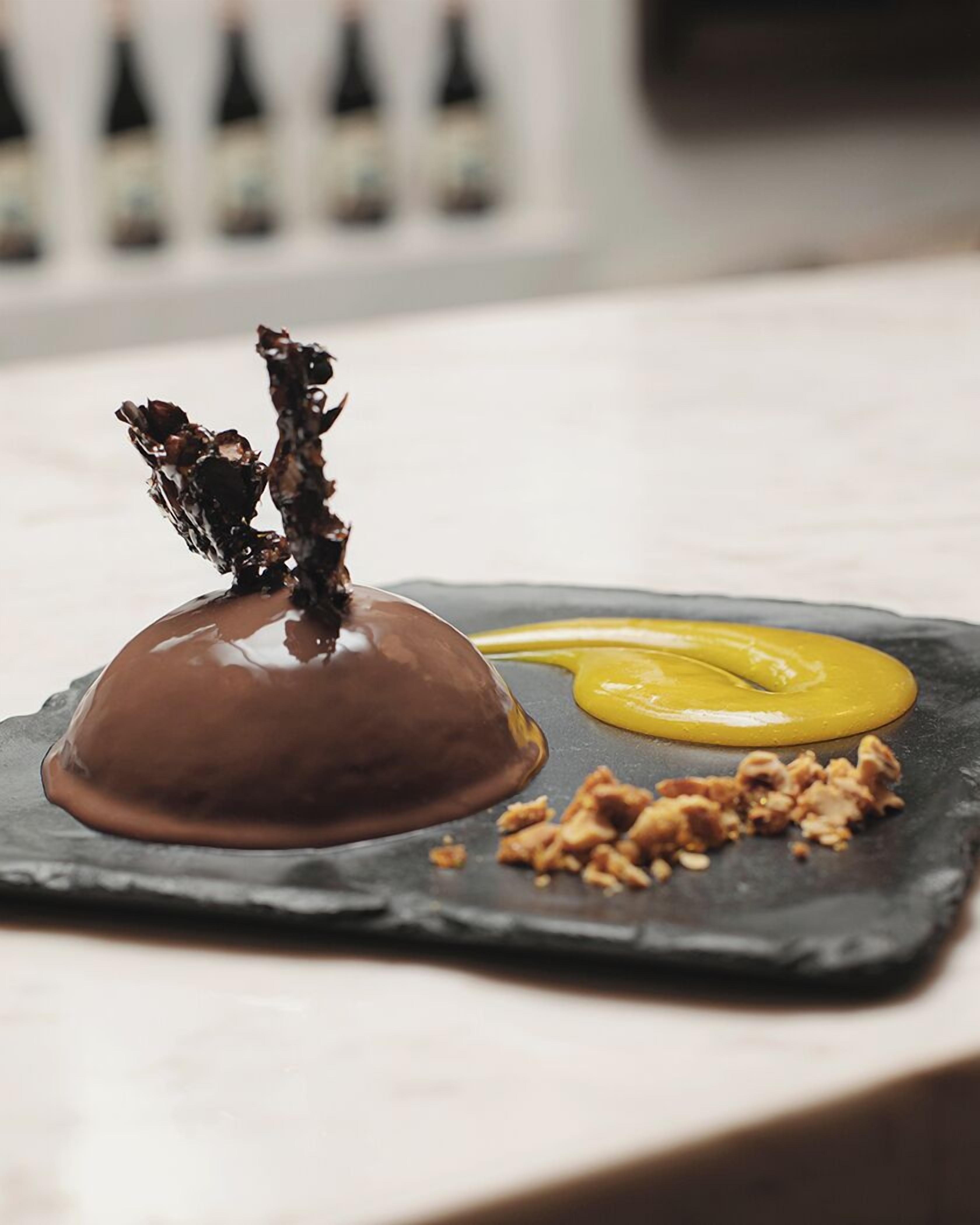 A dessert on a slate plate with a caramelized topping and a dollop of yellow sauce.