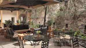 Ein überdachter Patio-Bereich mit Sitzgelegenheiten im Freien, Steinmauern und Topfpflanzen.