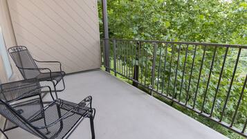 Un balcon avec des chaises en métal et une vue sur un espace verdoyant et arboré.
